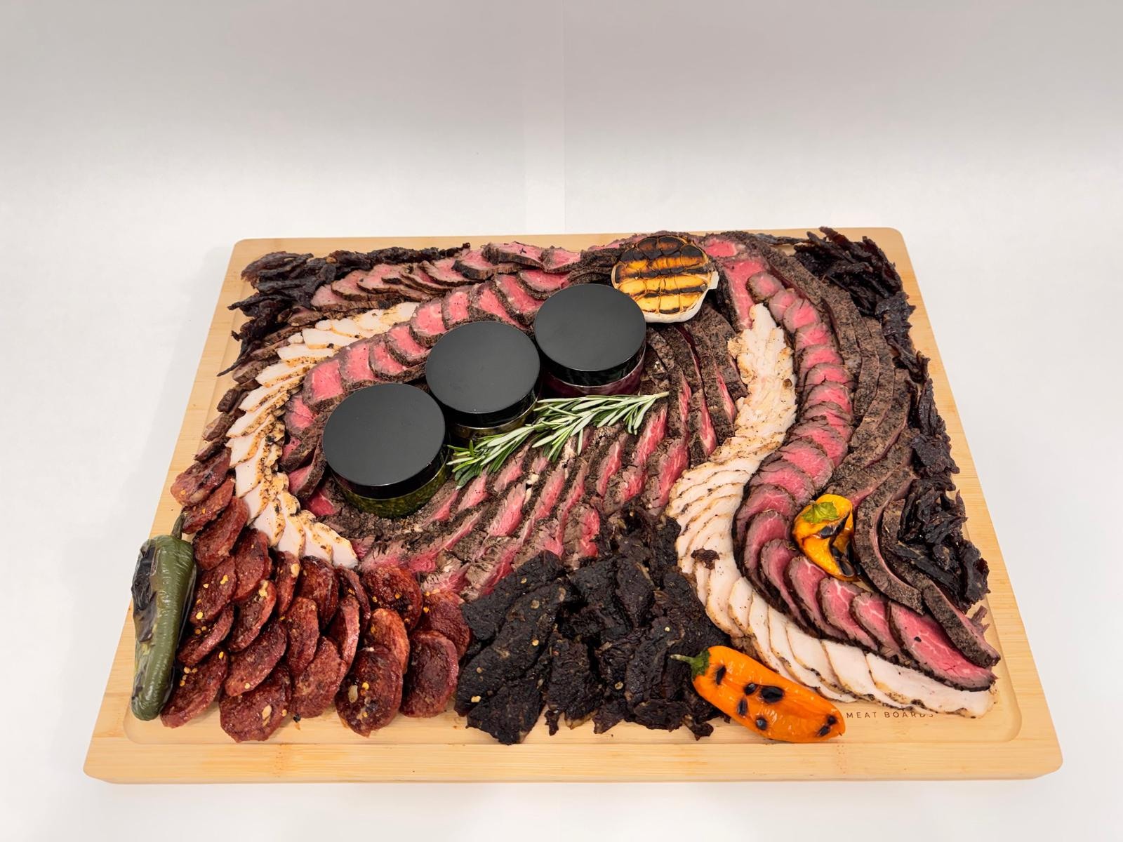 The Inferno meat board with sliced steak, chicken, salami, jerky, and jars of homemade accompaniments